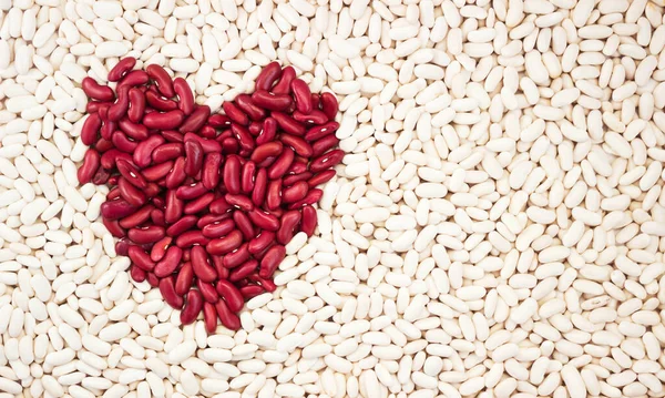 豆の背景 白い豆の背景に赤い豆の心 ゲームの愛の背景 — ストック写真