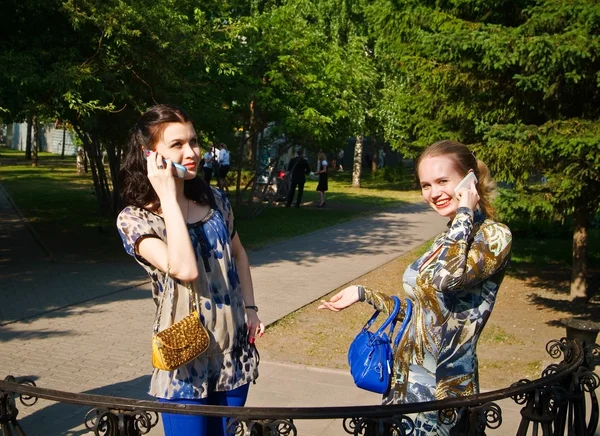 Skönhet unga kvinnor samtal från mobiltelefoner på parken — Stockfoto