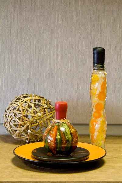 Decorative bottles, straw sphere and the ceramic plate on the ta — Stock Photo, Image