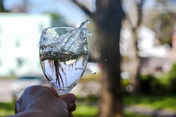 Hand Hält Glas Mit Wasserspritzer Freien Mit Defokussiertem Hintergrund — Stockfoto