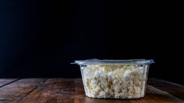 Feta peyniri plastik kapta, cam kenarındaki ahşap masada fotokopi alanı ile.