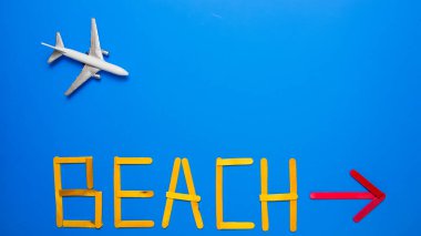 Blue background with toy airplane and text beach with red arrow