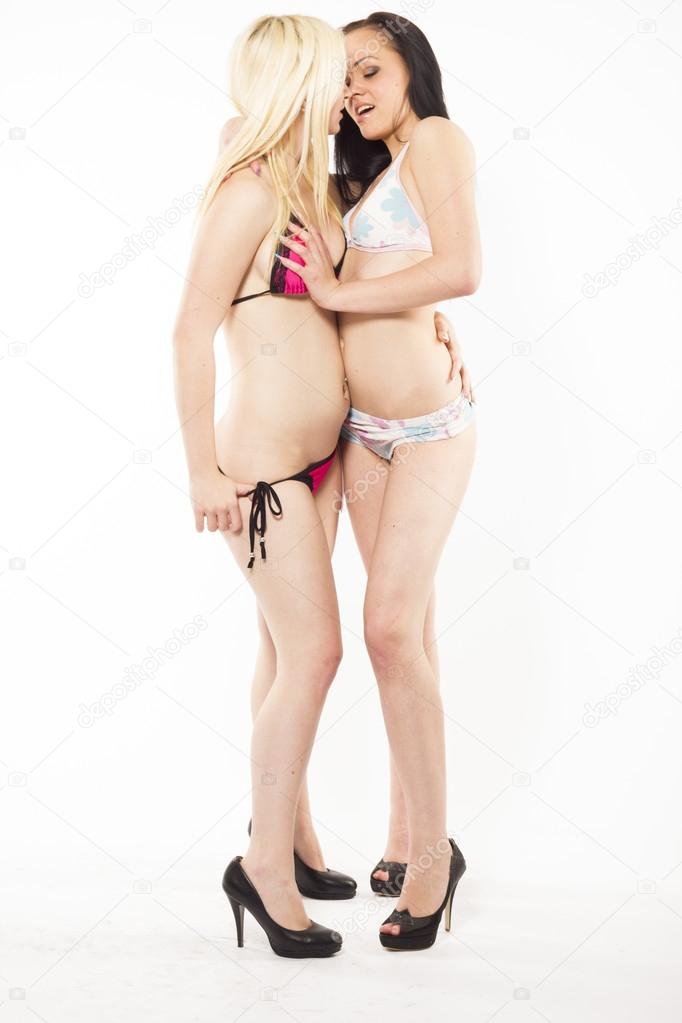 Sexy lesbian couple on white isolated background - blonde and brunette slim women close to each other