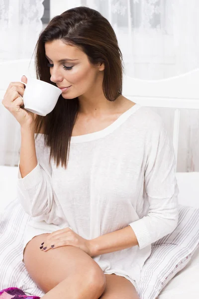 Young woman with morning coffee on the bed — Stock Photo, Image