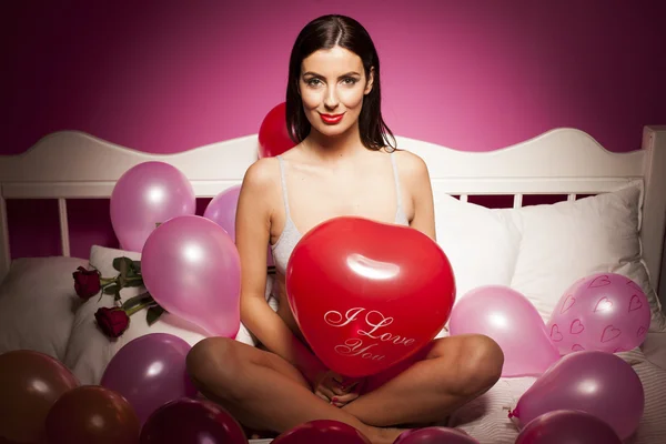 Sexy lingerie vrouw met de dag van Valentijnskaarten decoraties op het bed — Stockfoto
