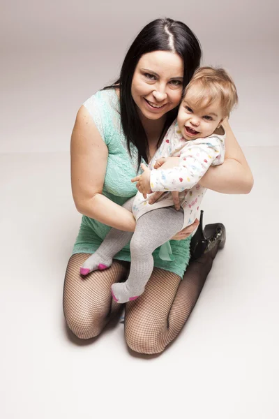 Cute baby child with her mother on gray isolated background — Stock Photo, Image