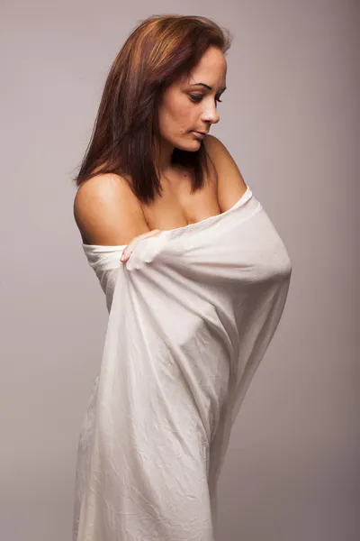 Sexy brunette woman with perfect body covered with white transparent textile on gray isolated background — Stock Photo, Image