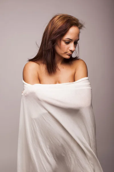 Sexy brünette Frau mit perfektem Körper mit weißen transparenten Textilien auf grauem isolierten Hintergrund bedeckt — Stockfoto