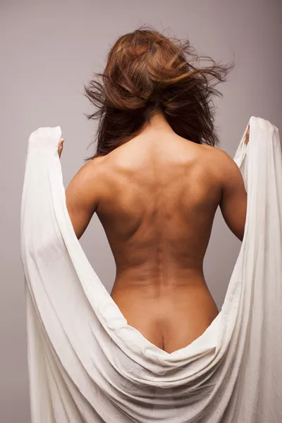 Mulher morena sexy com corpo perfeito coberto com tecido transparente branco em fundo isolado cinza — Fotografia de Stock