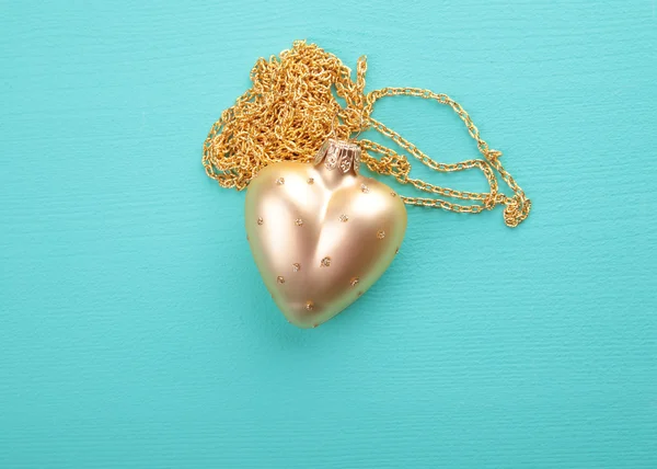 Gold heart with gold chain on the wood texture — Stock Photo, Image