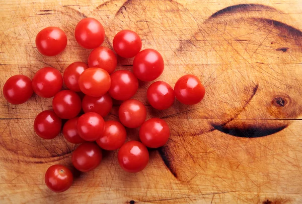 Tomates rojos cereza en una tabla de madera — Foto de Stock