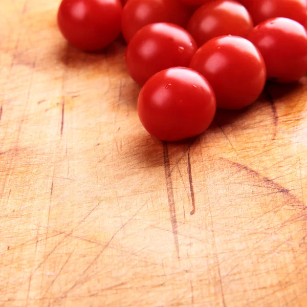 Tomates cerises rouges sur une planche en bois — Photo