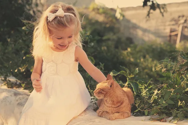 küçük kız kırmızı kedi okşayarak