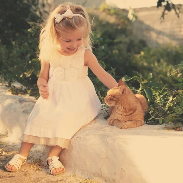 küçük kız kırmızı kedi okşayarak