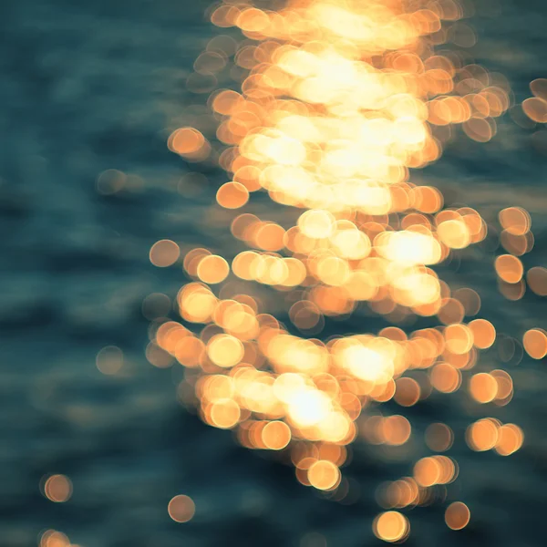 Goldene Sonnenlichter auf blauem Wasserhintergrund. — Stockfoto