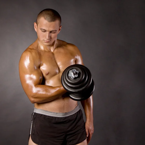 Musculado masculino fisiculturista dumbbell swing — Fotografia de Stock
