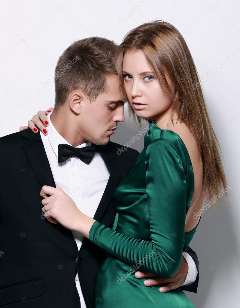 Portrait of young couple in love posing at studio dressed in cla