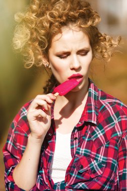 Dondurmayı parlak güneşin altında yemek ekose gömlekli kız