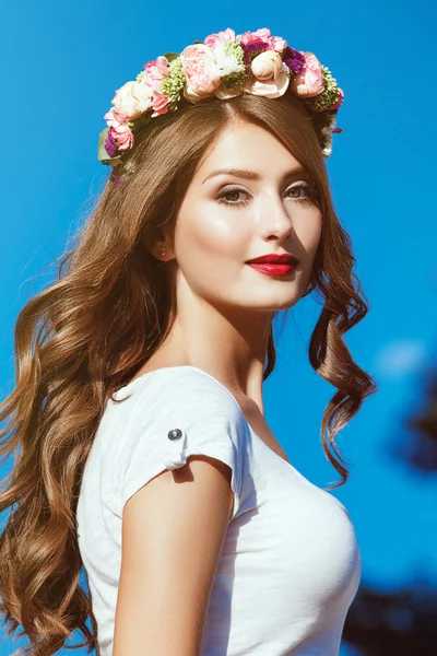 Beautiful brunette with long curly hair in a wreath of flowers p — Stock Photo, Image