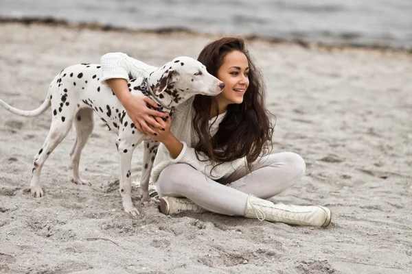 Happy young woman resting at beach in autumn with dog — Stock Photo, Image