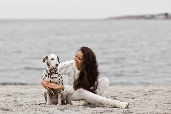 Mutlu genç kadını kumsalda sonbaharda köpekle dinleniyor. — Stok fotoğraf