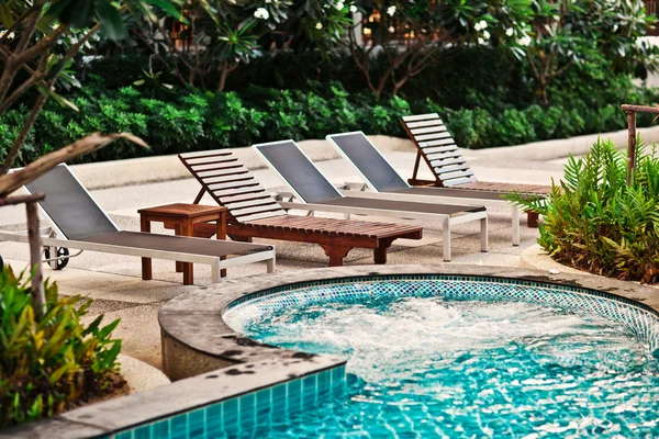 Liegestühle in der Nähe von Schwimmbad in tropischen Resort, Thailand. — Stockfoto