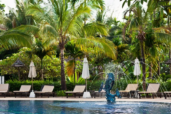 Beach chairs near swimming pool in tropical resort, Thailand.