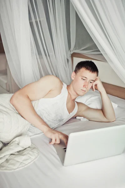 彼のラップトップでベッドに横たわっている男 — ストック写真