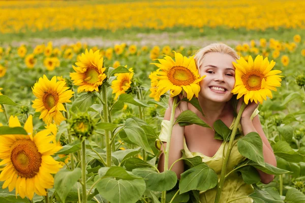 Schöne langhaarige junge Frau auf dem Feld mit Sonnenblumen — Stockfoto