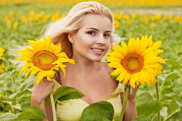 Hermosa mujer joven de pelo largo en el campo con girasoles —  Fotos de Stock