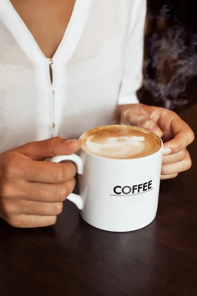 Ahşap masada latte taşıyan kadın elleri. — Stok fotoğraf