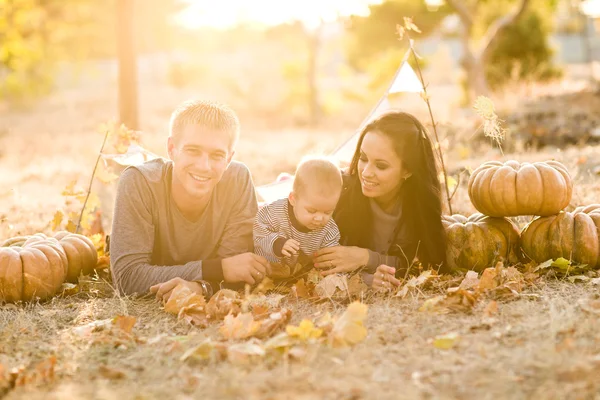 ครอบครัวที่มีความสุขกับฟักทองบนใบไม้ร่วง กลางแจ้ง . — ภาพถ่ายสต็อก