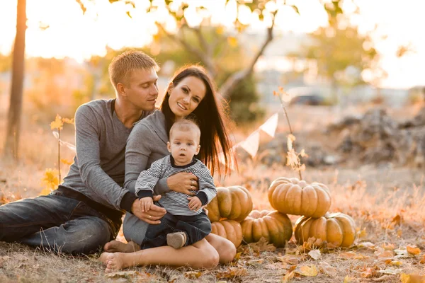 Familia feliz con calabaza en hojas de otoño. Exterior . —  Fotos de Stock