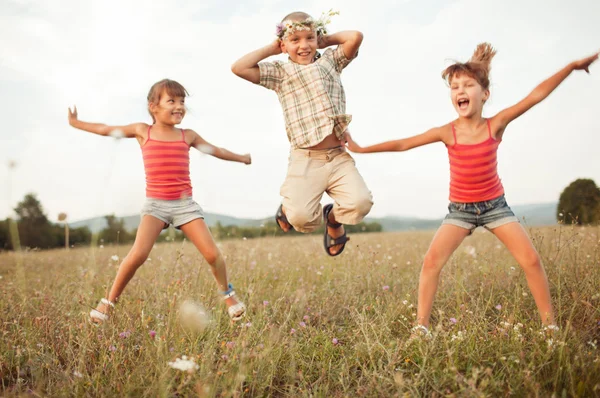 กระโดดเด็กบนทุ่งหญ้าแสงแดดที่สวยงามในฤดูใบไม้ร่วง — ภาพถ่ายสต็อก