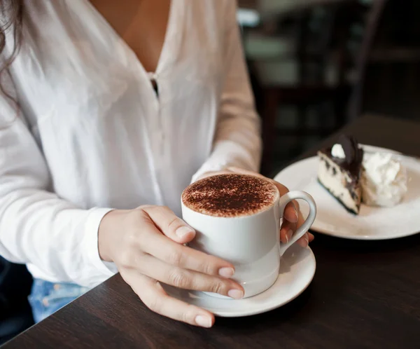 Woman hands with cappuccino on a wood table — Stok fotoğraf