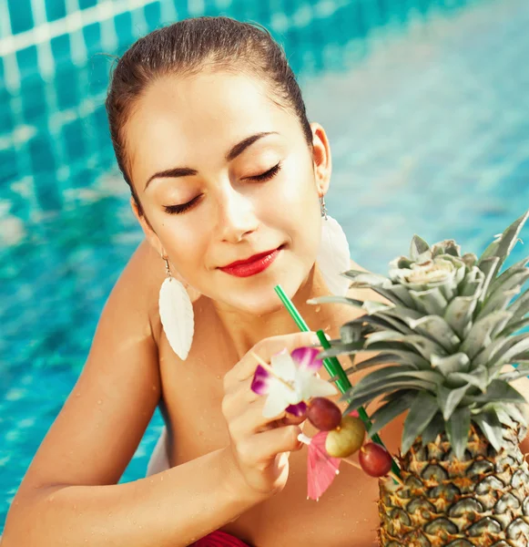 Mujer joven con cóctel fresco en la piscina — Foto de Stock