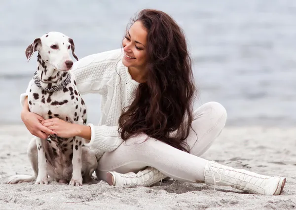 Kumsalda köpeği olan genç bir kadın.