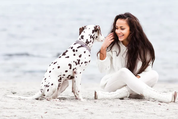 Kumsalda köpeği olan genç bir kadın. — Stok fotoğraf