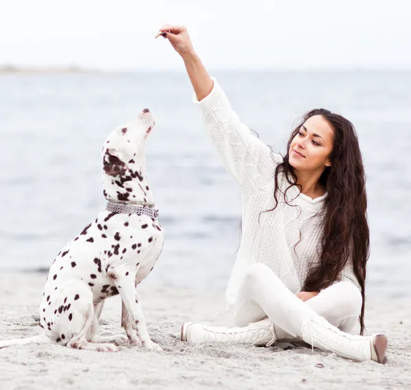 Kumsalda köpeği olan genç bir kadın. — Stok fotoğraf