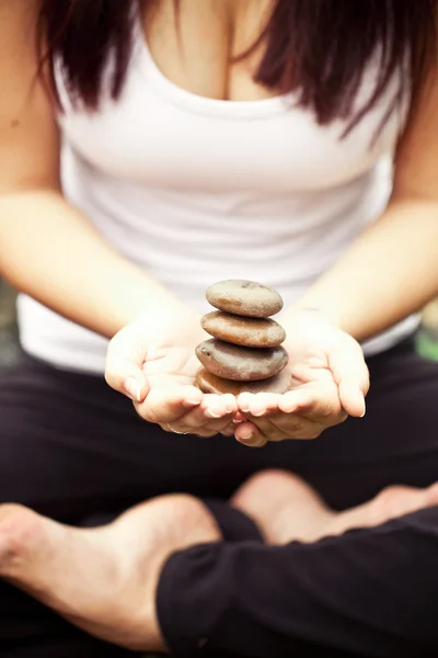 Spiritual fit woman sitting in lotus pose on a river stone