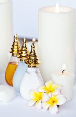 Masaj yağı ve balsam kase, havlu ve mum ile üç plumeria çiçek