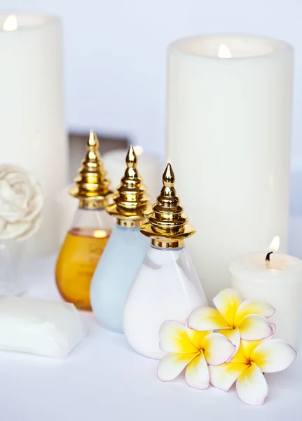 Três Plumeria flor com óleo de massagem e bálsamo em tigela, toalha e vela — Fotografia de Stock