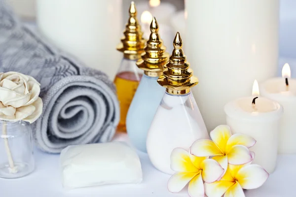 Trois fleurs de Plumeria avec huile de massage et baume dans un bol, serviette et bougie — Photo