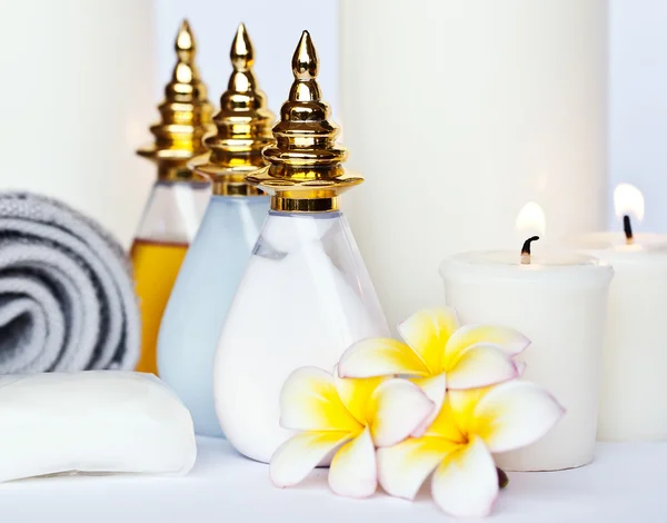 Three Plumeria flower with massage oil and balsam in bowl , towel and candle — Stock Photo, Image