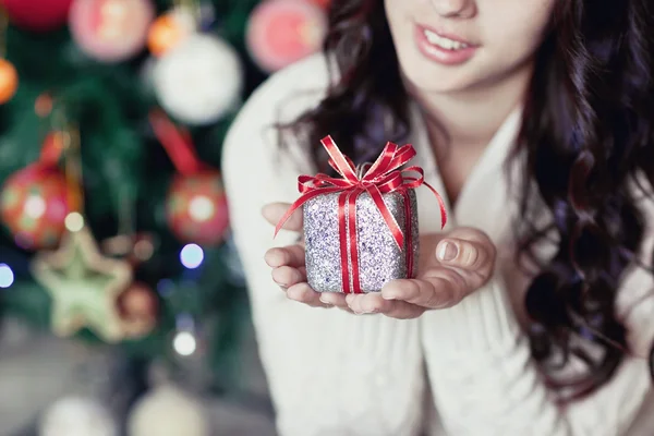 Jonge mooie vrouw onder nieuwe jaar boom met kerstcadeau — Stockfoto