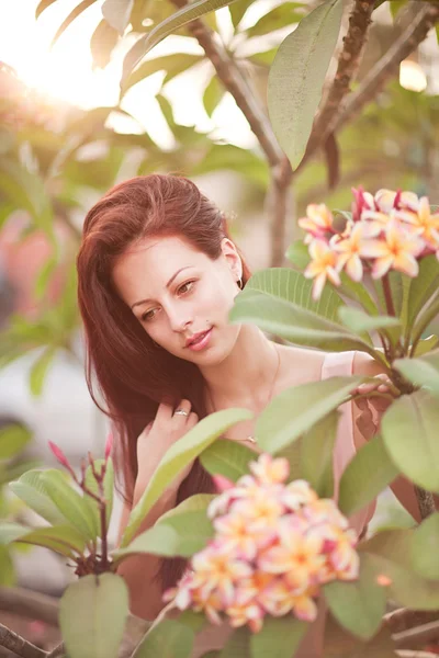 Mujer joven con flor tropical Plumeria alba — Foto de Stock
