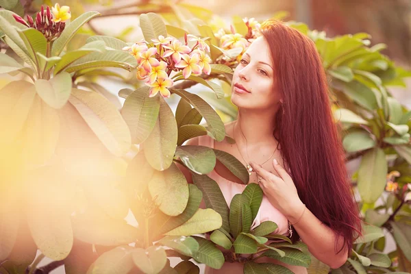 Ung kvinna med tropisk blomma plumeria alba — Stockfoto
