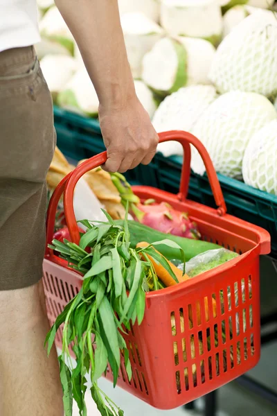 Muž s košíkem plné potravin v supermarketu — Stock fotografie