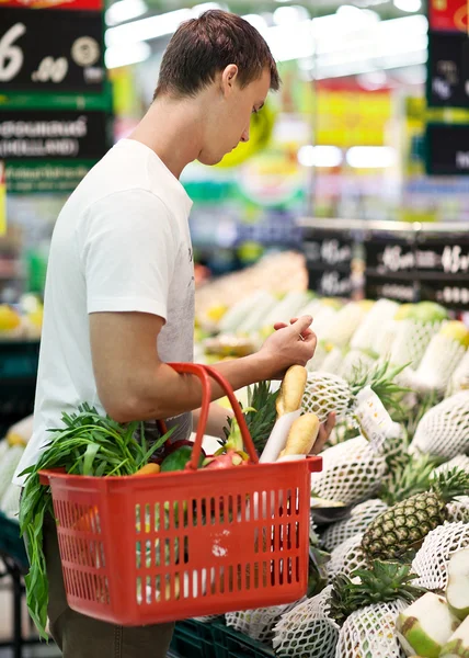 Hombre con canasta llena de comida en el supermercado — Foto de Stock