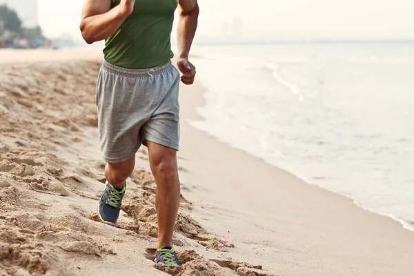 Atletische jongeman uit te oefenen en draait op het strand — Stockfoto